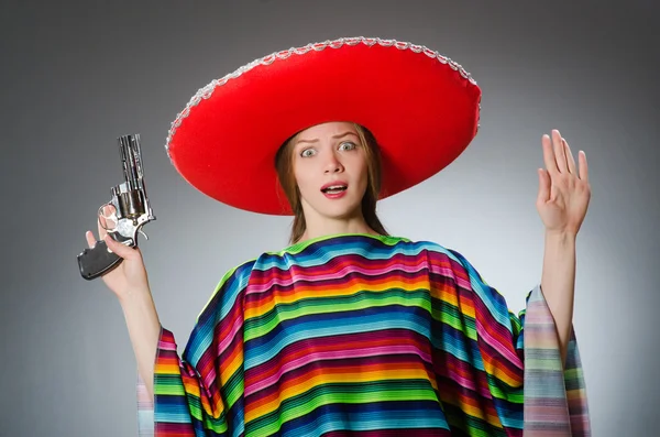 Mädchen im mexikanischen lebendigen Poncho hält Handfeuerwaffe gegen Grau — Stockfoto