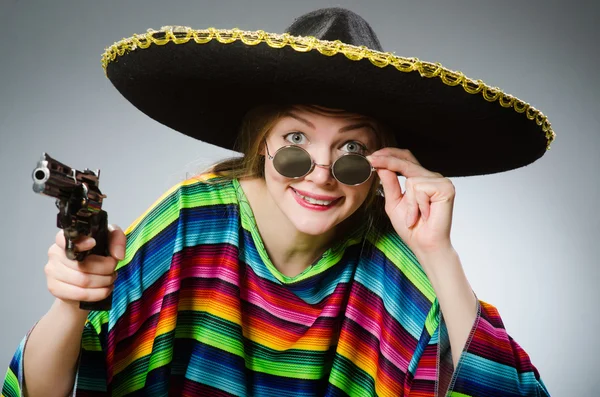 Chica en poncho mexicano vívido con pistola contra gris — Foto de Stock