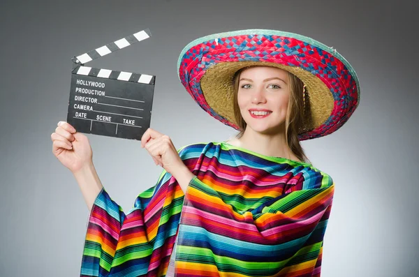 Chica en mexicano vívido poncho celebración clapboard contra gris —  Fotos de Stock