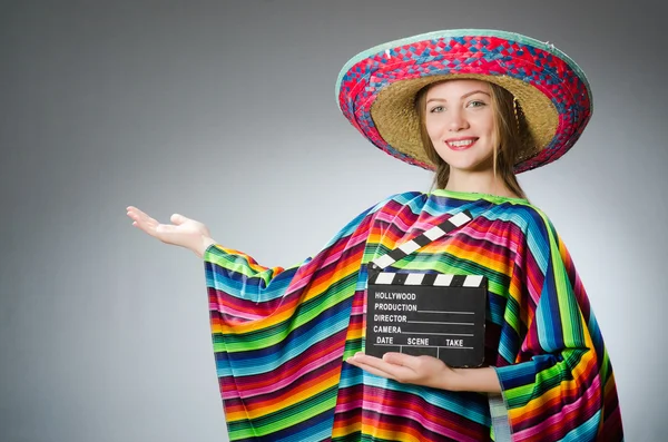 Menina em mexicano poncho vívido segurando palmas contra cinza — Fotografia de Stock