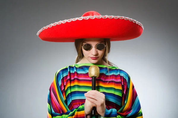 Menina em mexicano poncho vívido com maracas contra cinza — Fotografia de Stock