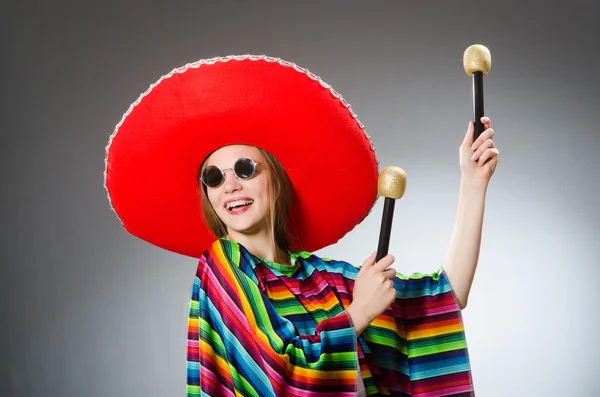 Menina em mexicano poncho vívido com maracas contra cinza — Fotografia de Stock