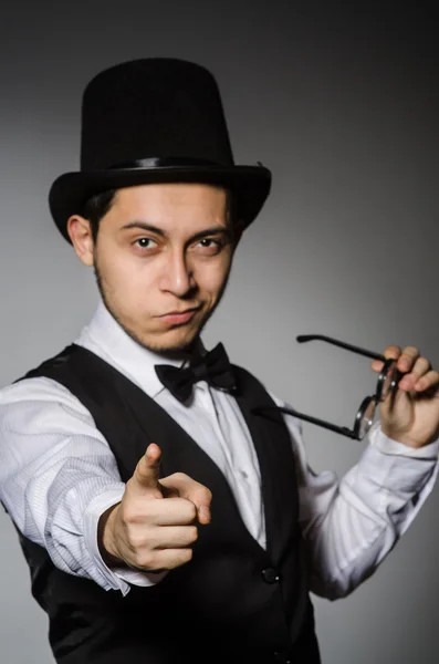 Mladý muž v klasické černé vestě a klobouk proti šedé — Stock fotografie