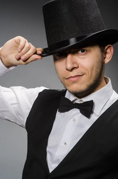 Молодий чоловік в класичному чорному жилеті і капелюсі проти сірого — стокове фото
