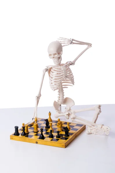 Скелет играет в шахматы на белом — стоковое фото