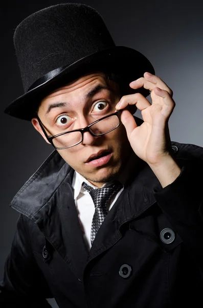 Joven con abrigo negro y sombrero contra gris — Foto de Stock