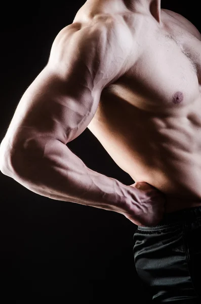 Muscular man posing in dark studio — Stock Photo, Image