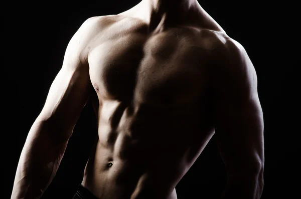 Uomo muscolare in posa in studio scuro — Foto Stock