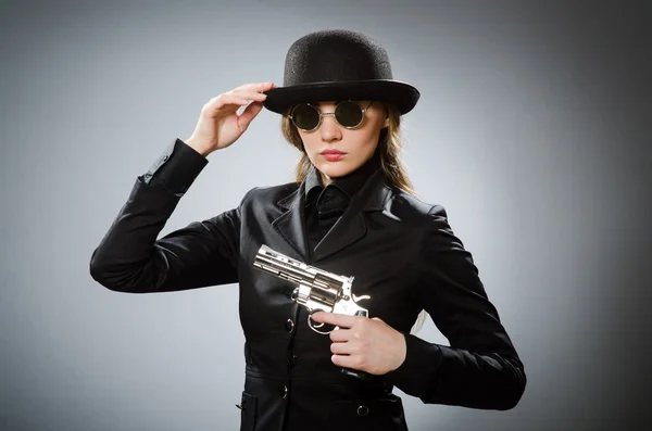 Female spy with weapon against gray — Stock Photo, Image