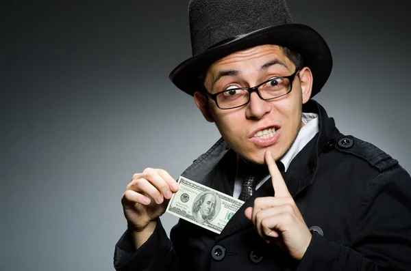 Young man in black coat holding money against gray — Stock Photo, Image