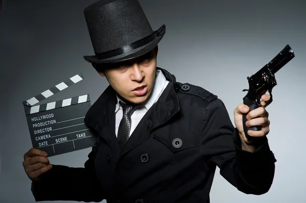 Young man with weapon and clapboard against gray — Stock Photo, Image