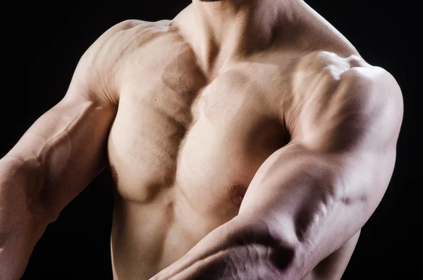 Hombre musculoso posando en estudio oscuro — Foto de Stock