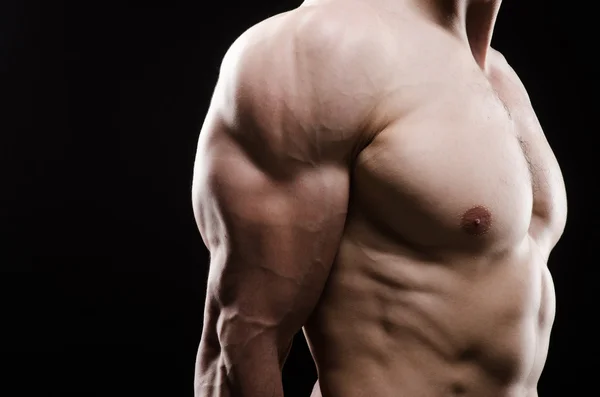 Hombre musculoso posando en estudio oscuro — Foto de Stock