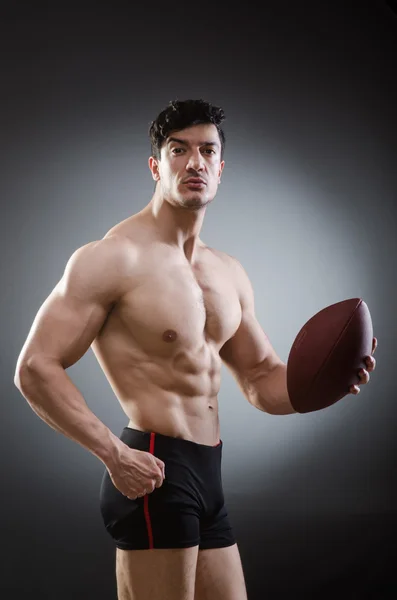 Мускулистый человек с американским футболом — стоковое фото