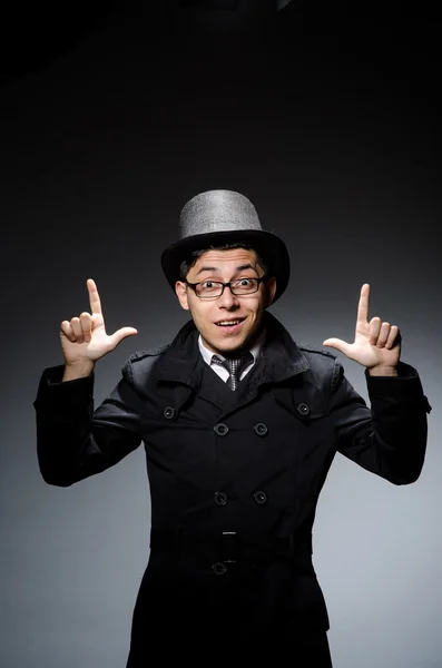Junger Mann in schwarzem Mantel und Hut gegen Grau — Stockfoto