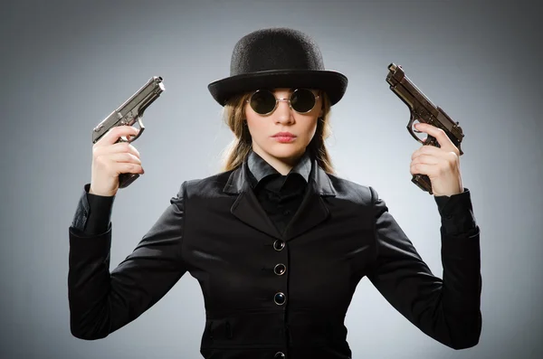 Vrouwelijke spion met wapen tegen grijs — Stockfoto