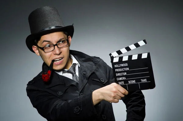 Detective de casaco preto com clapperboard contra cinza — Fotografia de Stock