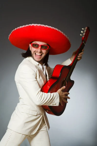 Mexicano engraçado em terno segurando guitarra contra cinza — Fotografia de Stock