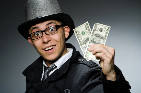 Young man in black coat holding money against gray — Stock Photo, Image