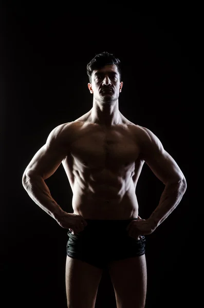 Hombre musculoso posando en estudio oscuro — Foto de Stock