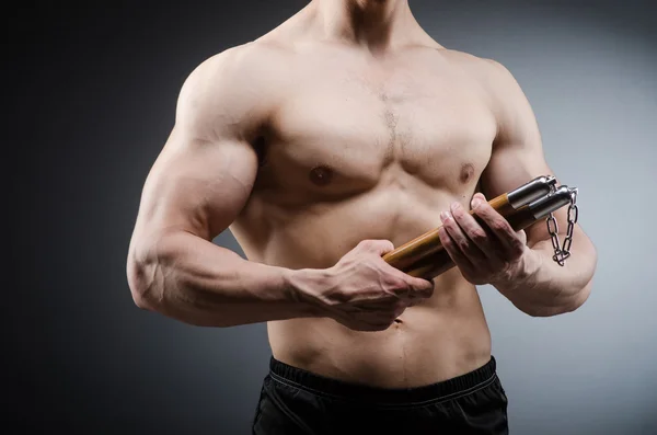 Muskulös stark man med nunchucks — Stockfoto