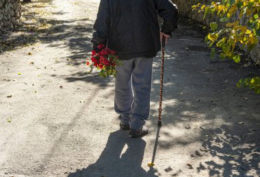 Yaşlı adam karısına çiçekler taşıyor..