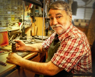 Yaşlı zanaatkar pirinç mühür için odun kabzasını kazıdı.