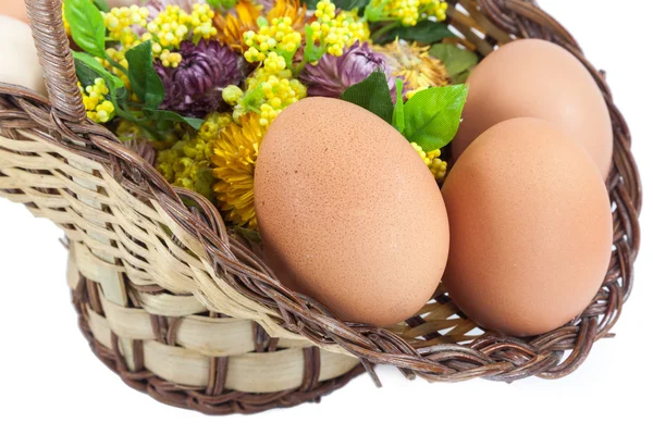 Ovos de Páscoa em cesta marrom com flores — Fotografia de Stock