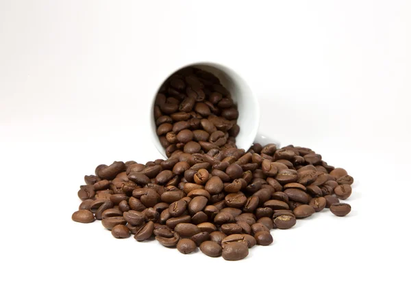 Copo virado com grãos de café no fundo branco — Fotografia de Stock