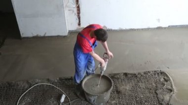 Worker preparing concrete grout for floor