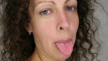 Yakın çekim portre olan kadın kıvırcık saçlar Dil Gösterilen