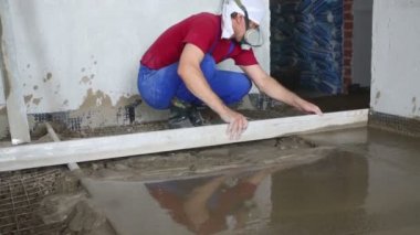 Worker makes overlay of concrete floor