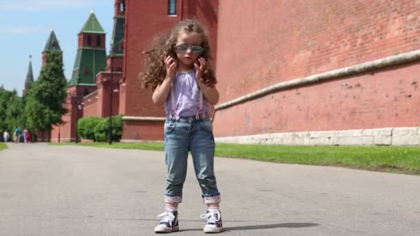 Маленькая девочка возле большой красной стены — стоковое видео