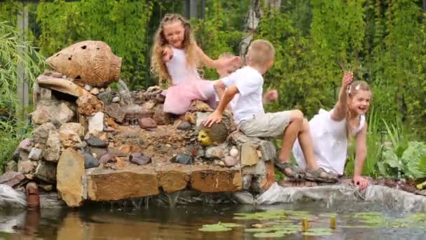 Jongens en meisjes spelen naast de vijver — Stockvideo