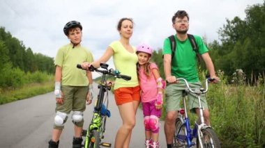 İki çocuk paten üzerinde durmak ve veliler ile Bisiklet stand