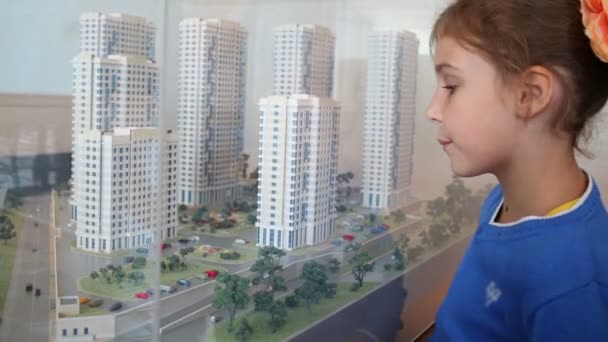 Girl  looks at layout of buildings — Stock Video