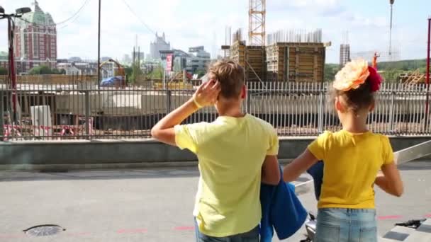 Мальчик и девочка смотрят на здания — стоковое видео