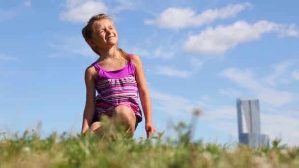 Feliz niña se sienta en la hierba — Vídeos de Stock