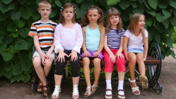 Дети сидят на скамейке — стоковое видео