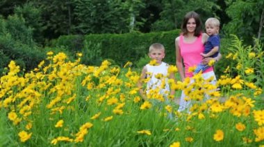 Anne ve iki oğlu flowerbed yakınındaki 
