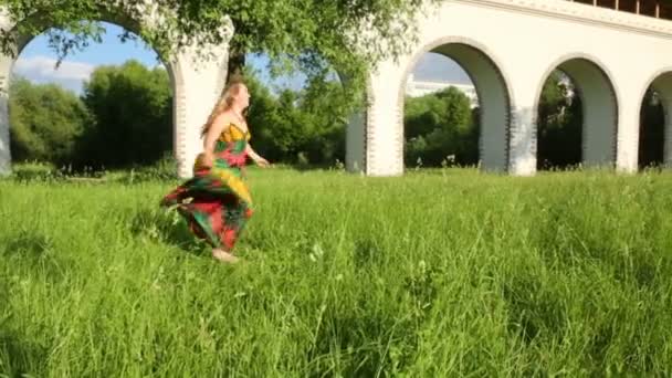 Девушка кружится и смотрит на траву — стоковое видео
