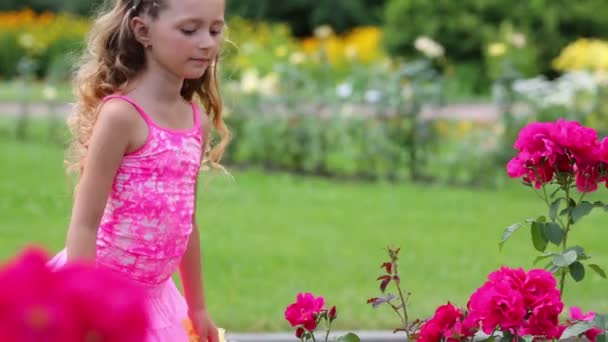 Kleines Mädchen schnüffelt rosa Blumen — Stockvideo