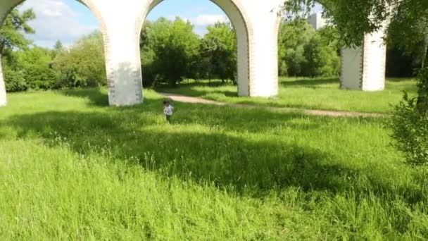 Mädchen und Junge laufen auf Gras — Stockvideo