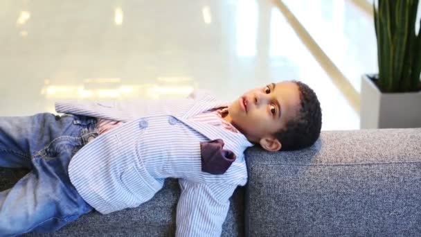 Boy in jacket lies on sofa — Stock Video