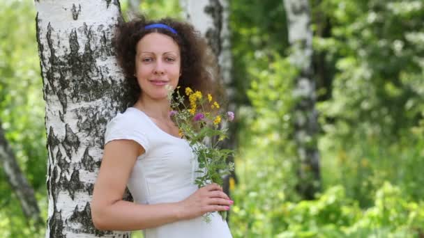 Молодая женщина нюхает полевые цветы — стоковое видео