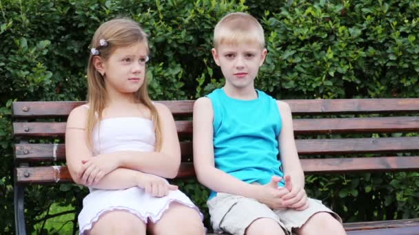 Niño y niña sentados en el banco — Vídeo de stock