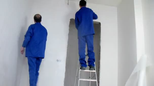 Deux travailleurs ont appliqué du plâtre sur les murs — Video