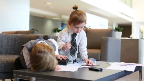 Boy plays with stapler and girl draws — Stock Video