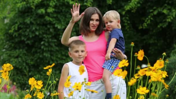 Mother and sons standing near flowerbed — Stock Video