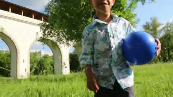 Niño con pelota camina sobre hierba — Vídeos de Stock